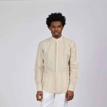 Man wearing a striped shirt and white pants against a plain background