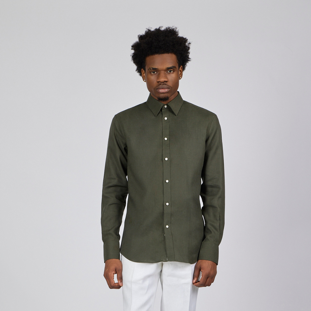 Man wearing a green shirt and white pants against a gray background