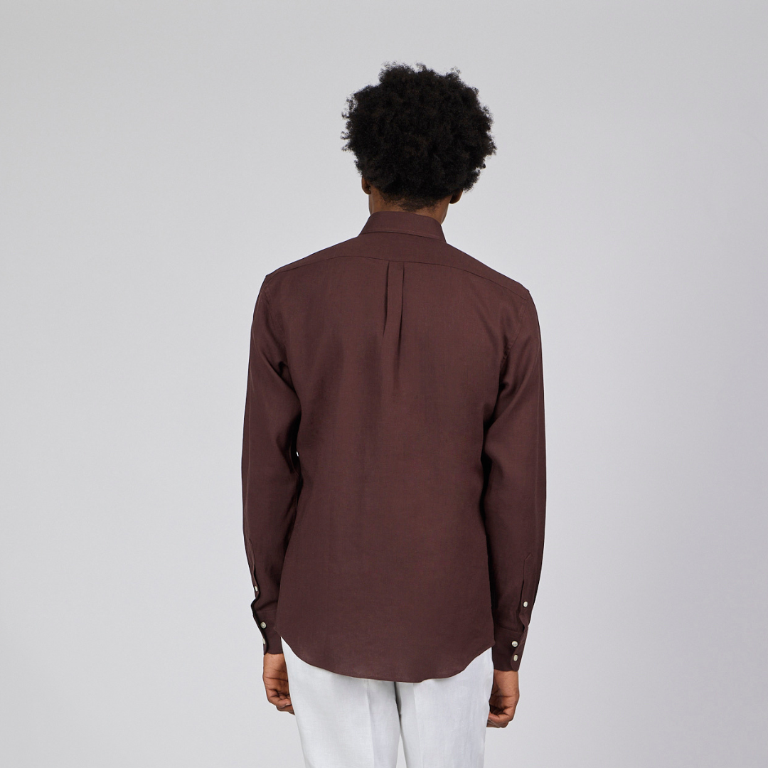 Person wearing a brown shirt and white pants on a plain background