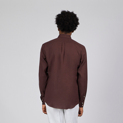 Person wearing a brown shirt and white pants on a plain background