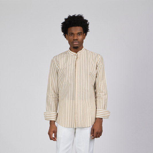 Man wearing a striped shirt and white pants against a plain background