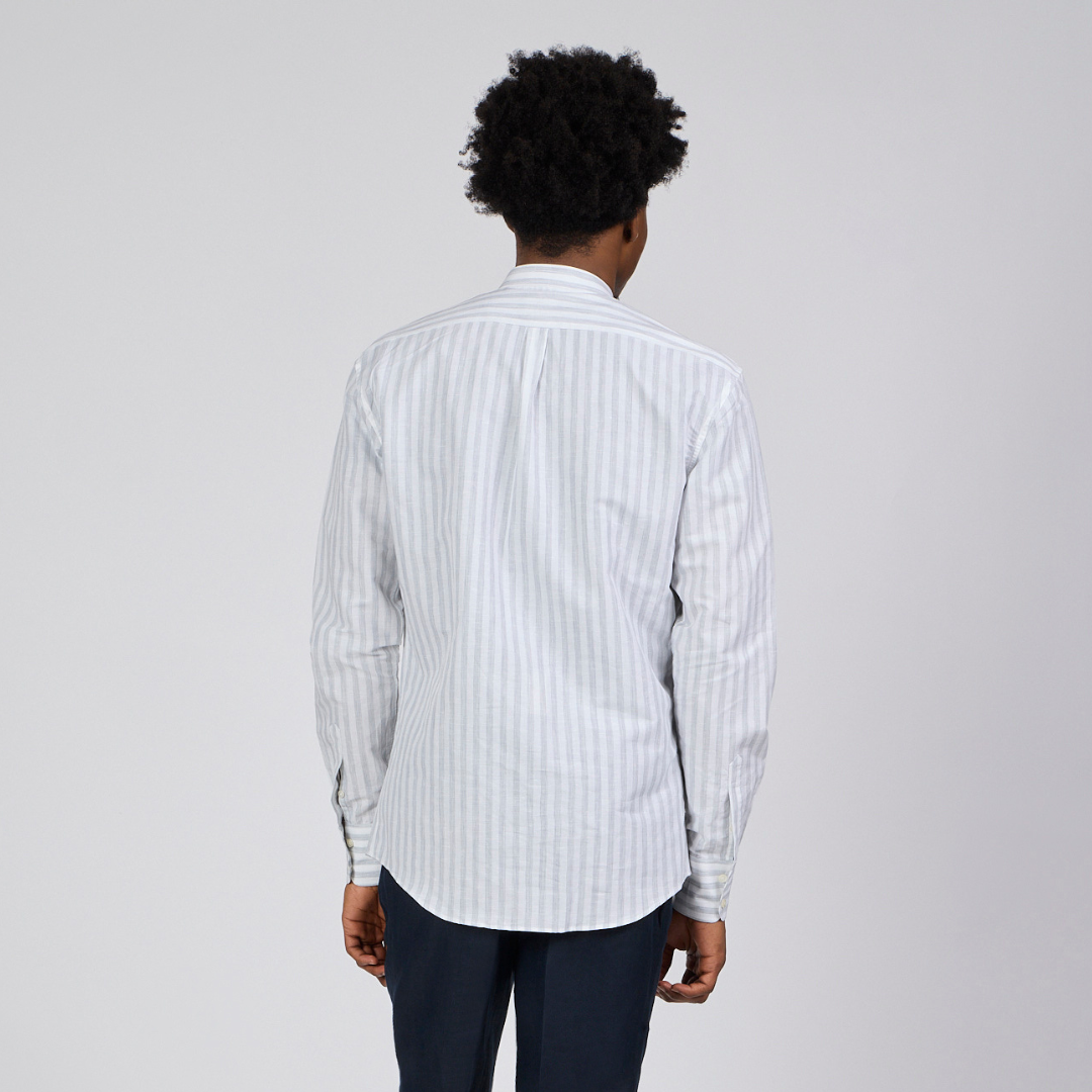 Man wearing a white striped shirt and dark pants on a white background