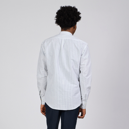 Man wearing a white striped shirt and dark pants on a white background
